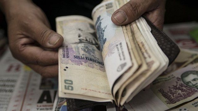 man counts Argentine pesos