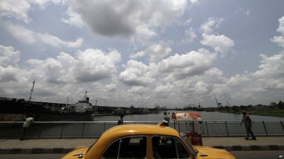 Rain clouds hover over as a cab plies through a bridge in Kolkata, India, Thursday, June 6, 2013. Monsoon rains are expected to arrive in the city in a week, according to weather officials