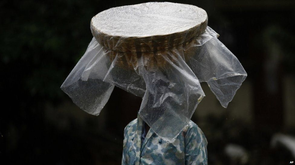 A fish vendor carries his basket on his head covered with plastic as he walks through a street during monsoon rains in Mumbai, India, on Sunday, June 9, 2013. The Southwest monsoon, arrived in the city Saturday, three days ahead of schedule, according to the meteorological department