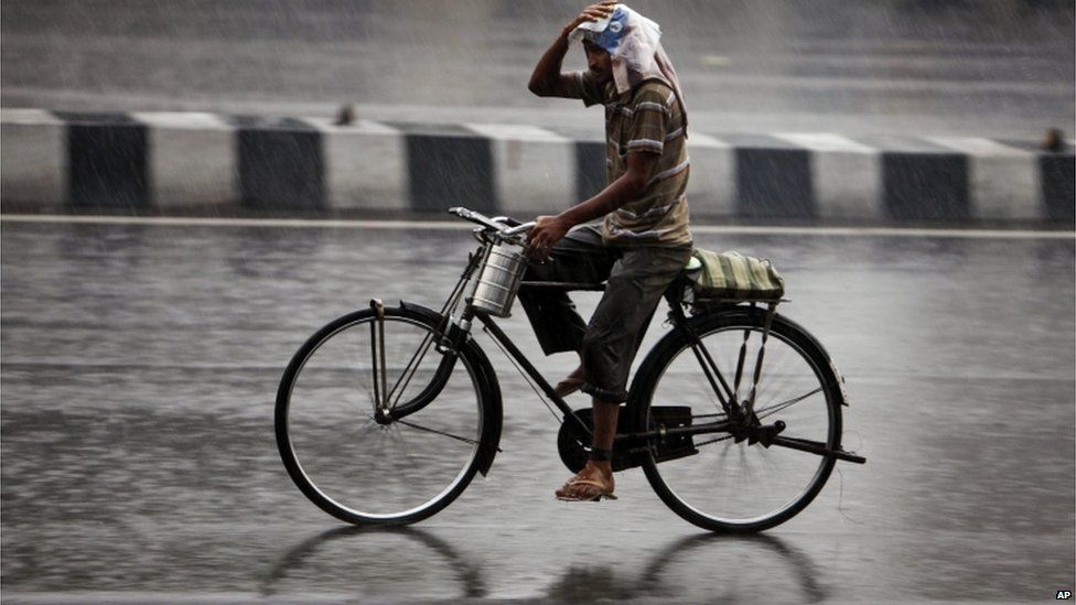 An Indian man on bicycle protects himself with a plastic bag from a heavy monsoon shower in Hyderabad, India, Saturday, June 8, 2013.