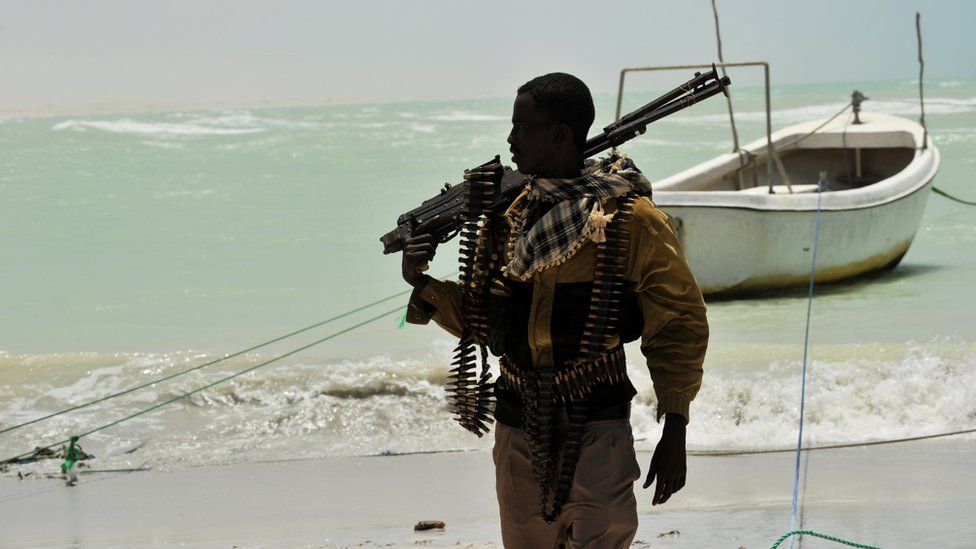 A Somali pirate carries a weapon on a beach in the central Somali town of Hobyo, 20 August 2010
