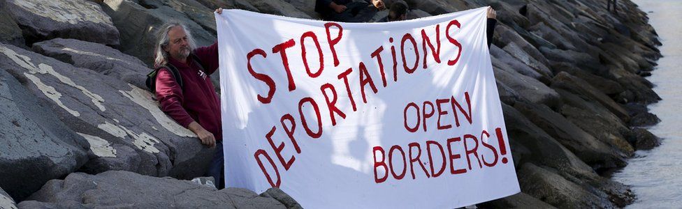 Activists hold a banner which says "Stop deportations, open borders" in the Turkish coastal town of Dikili