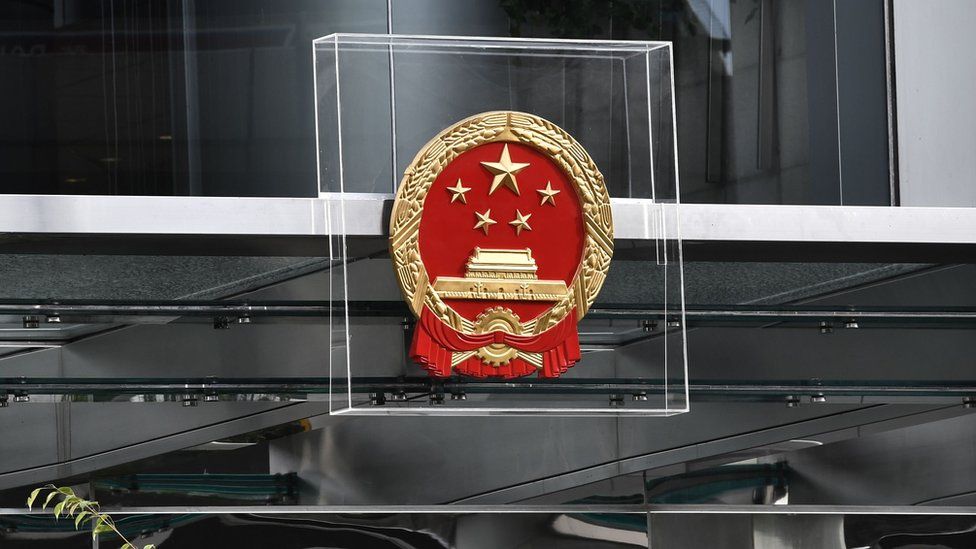 Police officers stand guard next to China's liaison office emblem being protected by plexiglass during a demonstration in Hong Kong on July 28, 2019.
