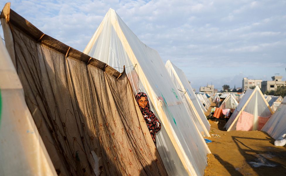 A displaced Palestinian woman stands between the tents in a camp where she is sheltering, in Rafah, southern Gaza Strip.