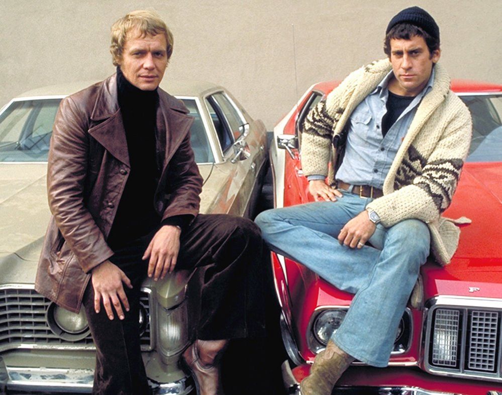 David Soul (left) and Paul Michael Glaser as Starsky & Hutch, leaning on the bonnets of their cars
