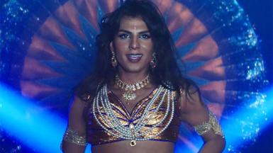 Actor Jason Patel as Asian drag queen Aysha looking at the camera wearing pearls and gold jewellery