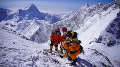A team of four mountain rescuers in climbing gear at altitude in snow on Everest