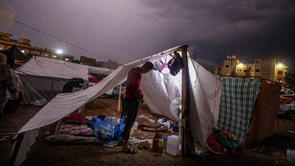 Palestinians who fled the northern Gaza Strip prepare their makeshift tents during a rainy night in Khan Younis town, southern Gaza Strip on 14 November 2023.