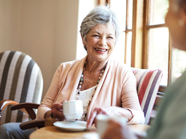 Older woman smiling and enjoying coffee