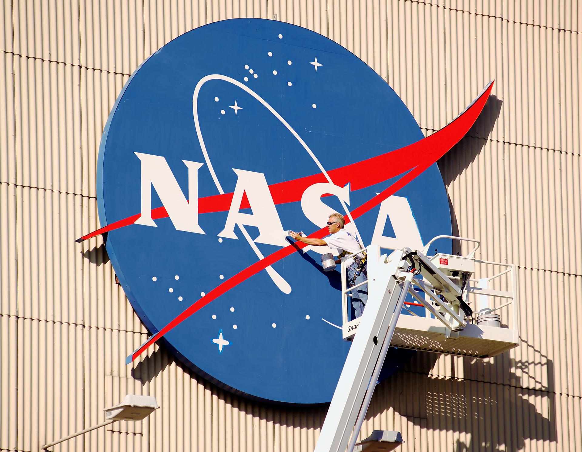 Painter applies fresh coat of paint to the NASA Meatball on the Hangar's North Facade
