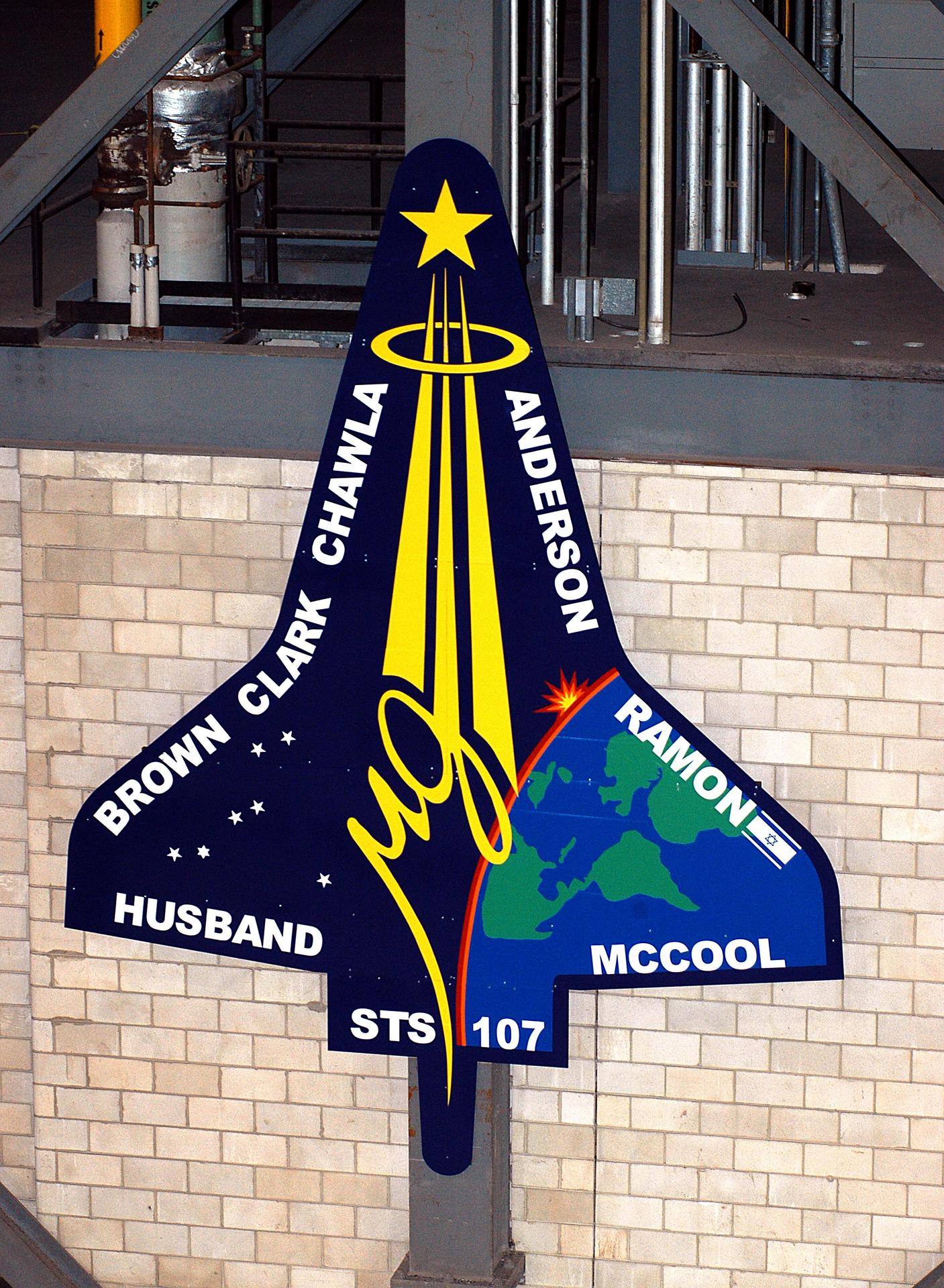 A large STS-107 mission insignia on a wall at KSC