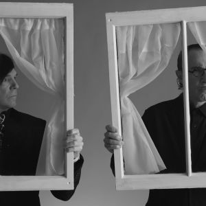 Ron ja Russell Mael eli popduo Sparks poseeraa mustavalkoisessa kuvassa ikkunankarmit kädessä. Kuva dokumenttielokuvasta The Sparks Brothers.