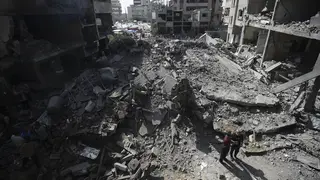 Palestinians look at the aftermath of an Israeli bombing in a refugee camp in the Gaza Strip