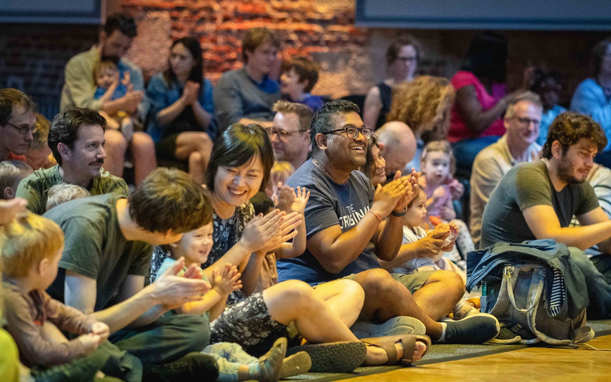 Toddlers with their parents and guardians, sitting on the floor and watching a Musical Storytelling Concert for Under-5s.