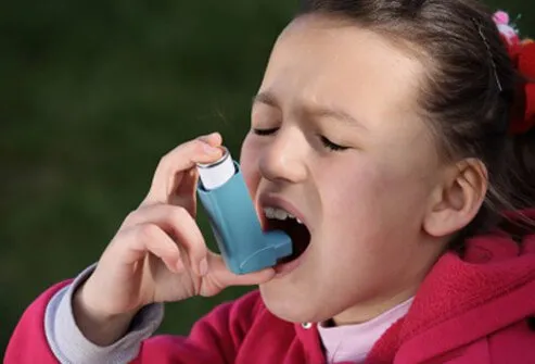 A young girl with allergic asthma uses her asthma inhaler. 