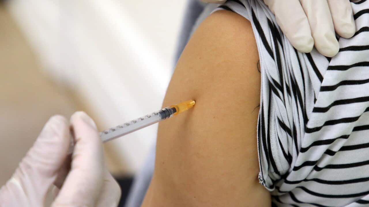 A gloved hand inserts a needle into a person's arm