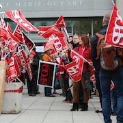 Un groupe de manifestants avec des drapeaux du SPGQ devant l'édifice Marie-Guyart à Québec.