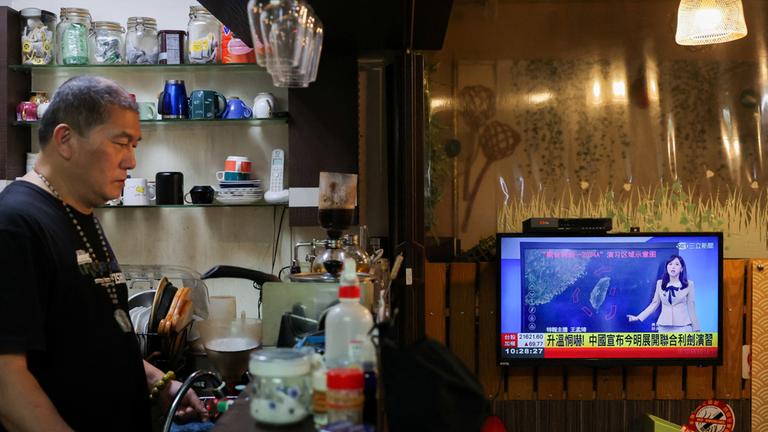 Ein Fernseher in einem Lokal zeigt die Verkündung des Manövers in den Nachrichten des chinesischen Fernsehens