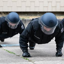  Polizeischüler machen in voller Montur Liegestütze. (Quelle: dpa/Paul Zinken)