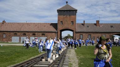 Menschen mit Israel-Flaggen stehen auf den Gleisen in Auschwitz.