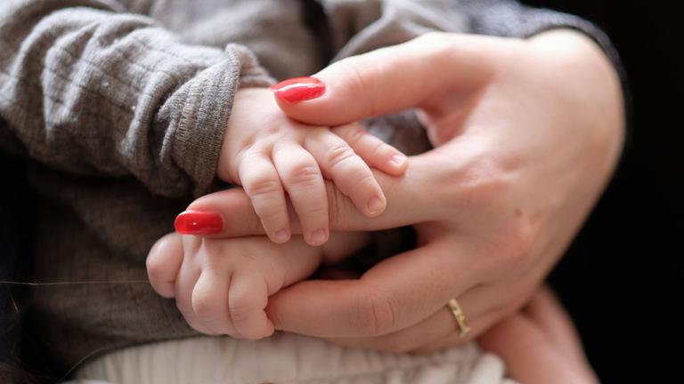 Eine Frau hält ein zwei Monate altes Baby im Arm (Symbolbild)