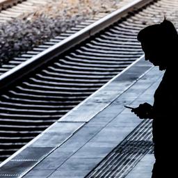 Symbolbild: Eine Frau steht am Berliner Bahnhof Ostkreuz am Bahnsteig und schaut auf das Handy. (Quelle: dpa/Christoph Soeder)