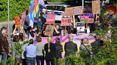 Teilnehmer der Demonstration "Vielfalt statt Einfalt - Schule ohne Diskriminierung" stehen mit Schildern und Plakaten vor dem Schulamt in Cottbus.