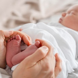 Eine Mutter hält die Füße ihres Neugeborenen.