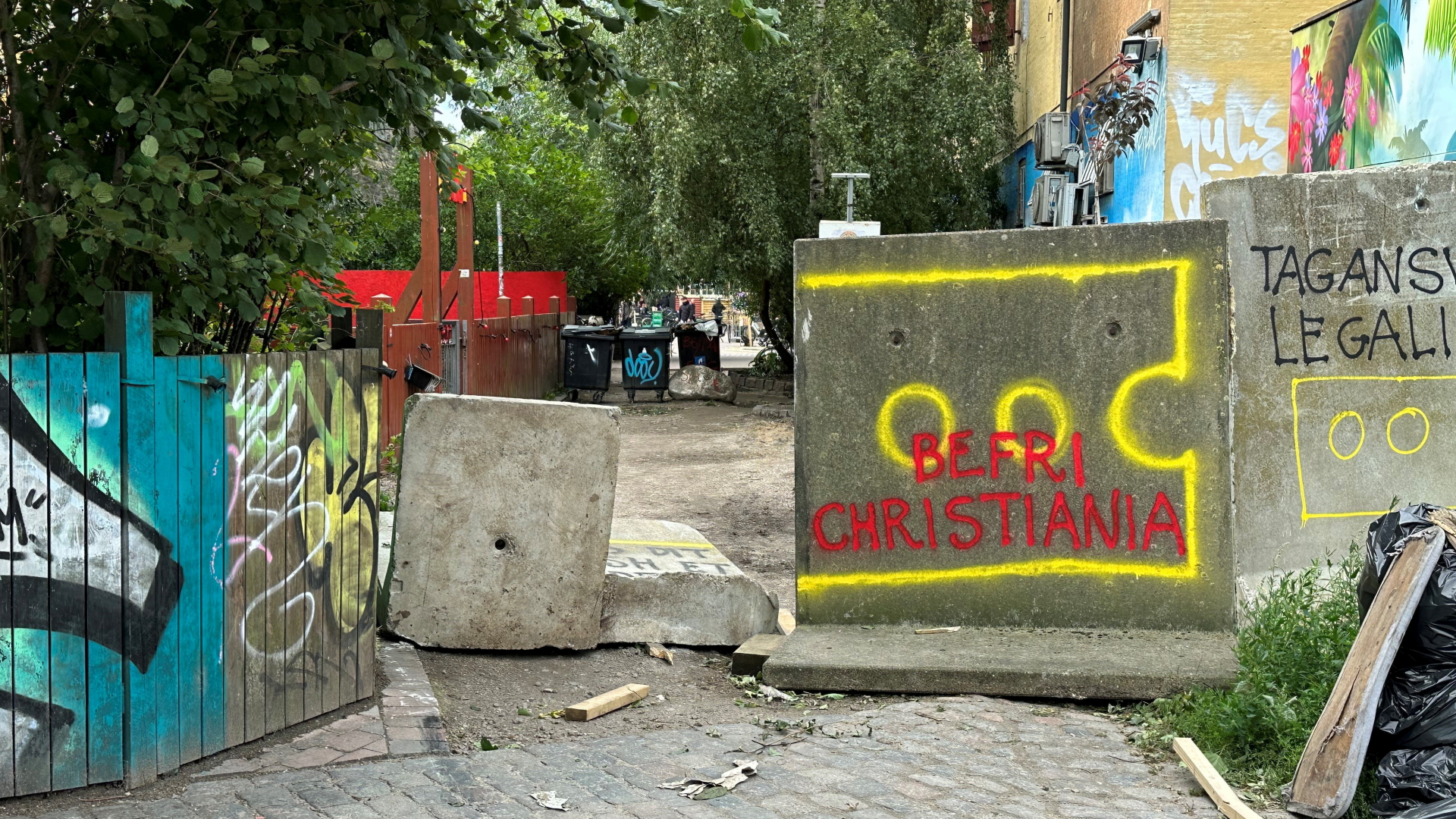 Auf einem grauen Betonblock, mit dem die "Pusher Street" teils blockiert wird, steht auf dänisch "Befreit Christiania".