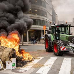 Ein Traktor steht neben einem brennenden Heuballen in Brüssel.