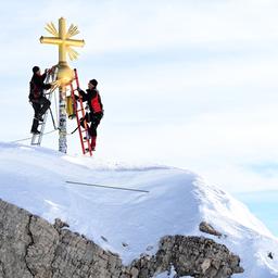 Die restaurierten Strahlen des Gipfelkreuzes der Zugspitze werden von Mitarbeitern wieder zum Gipfelkreuz gebracht.