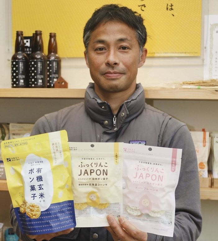 自社製品のポン菓子を手にする沢田米穀店の沢田導俊さん＝4月、北海道北斗市