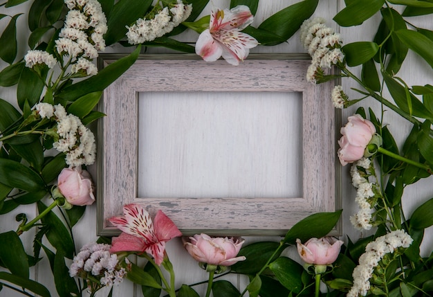 Free photo top view of gray frame with leaf branches and light pink flowers on a gray surface