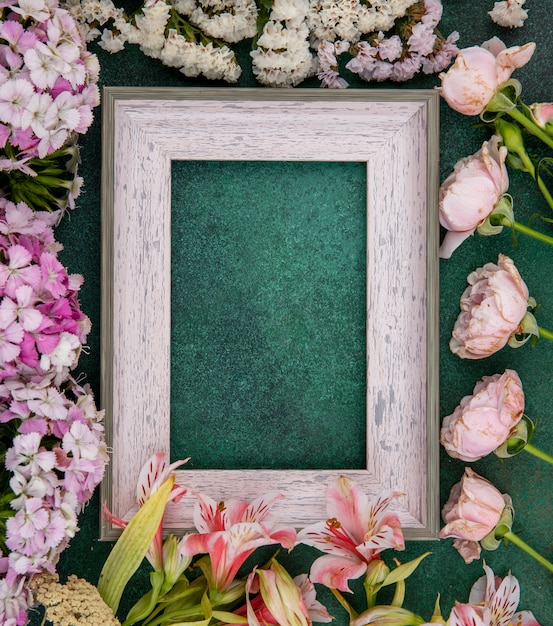 Free photo top view of gray frame with light pink flowers on a green surface