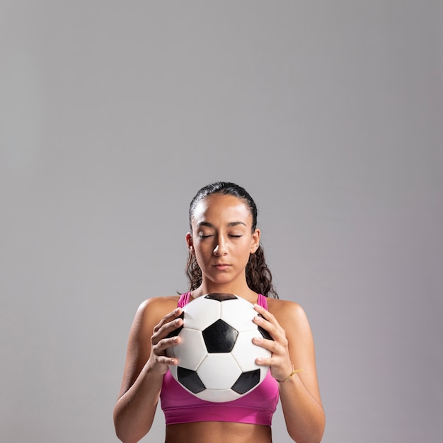 Подходящая женщина, держащая футбольный мяч