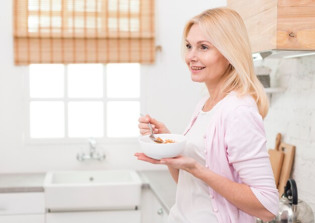 Lovely adult woman serving breakfast in the kitchen