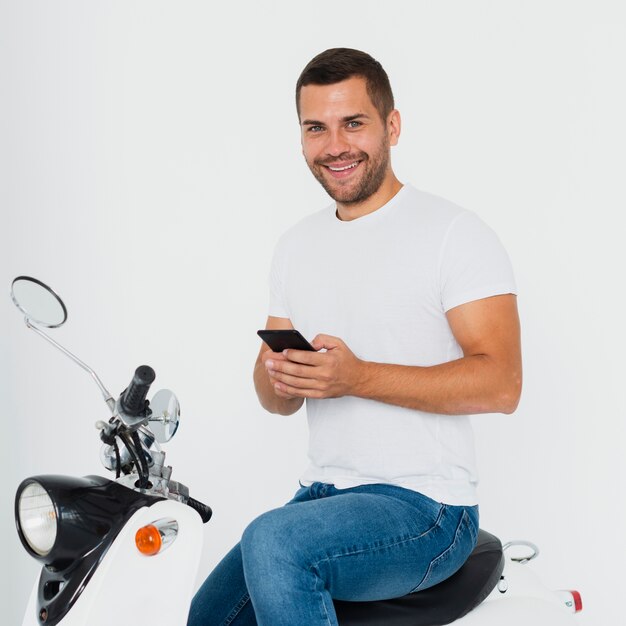 Man looking at camera and typing on his mobile phone