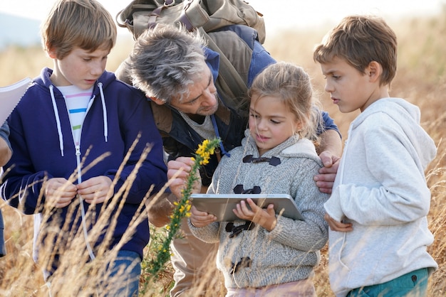 Teacher taking kids to countryside to explore plants and flowers 