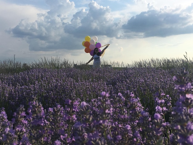 Фото Женщина с воздушными шарами, стоя на поле против неба