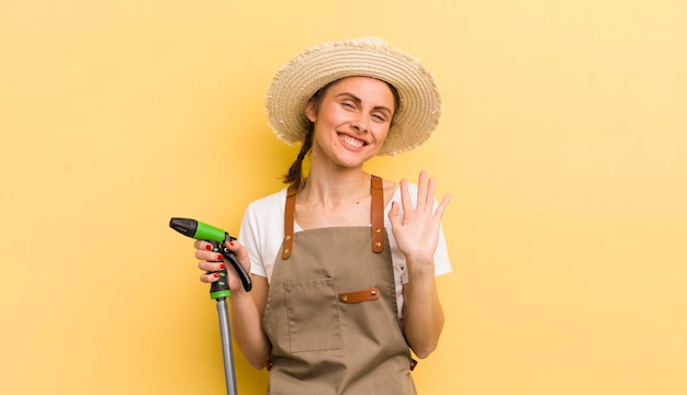 Фото Молодая красивая женщина счастливо улыбается, машет рукой, приветствуя и приветствуя вас в концепции садоводства