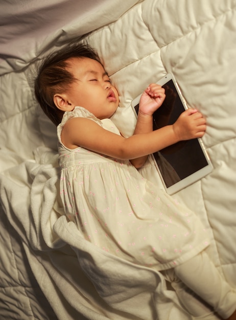 baby sleeping on bed after playing tablet
