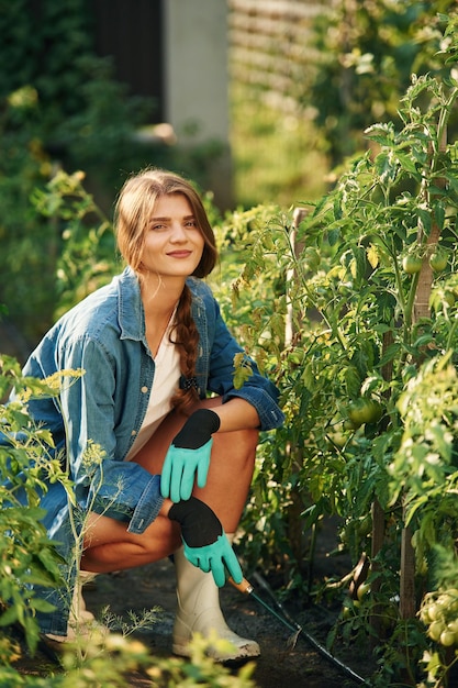 Фото Весело смотрит в камеру прекрасная молодая женщина занимается садоводством