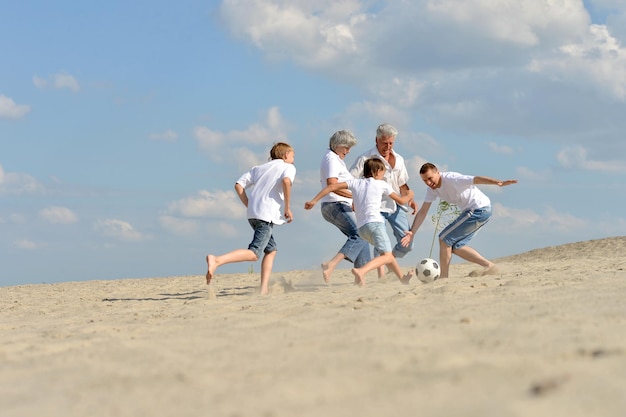 Семья играет в футбол на пляже