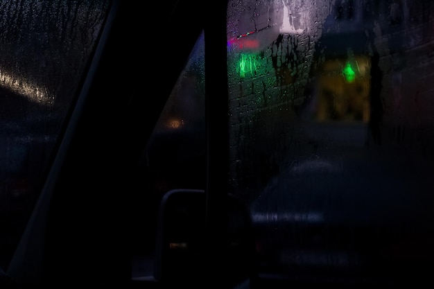 Side window of a car at night with raindrops
