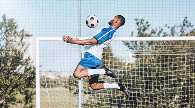 Спортивный футбол и мужчина прыгают с мячом, играя в игры, тренируясь и тренируясь на открытом поле.