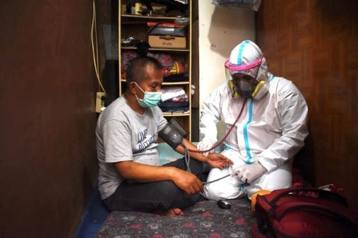 One on one: Wearing personal protective equipment, a physician (right) checks the health of a self-isolating man in Bandung on Aug. 14, 2021, amid the COVID-19 pandemic.