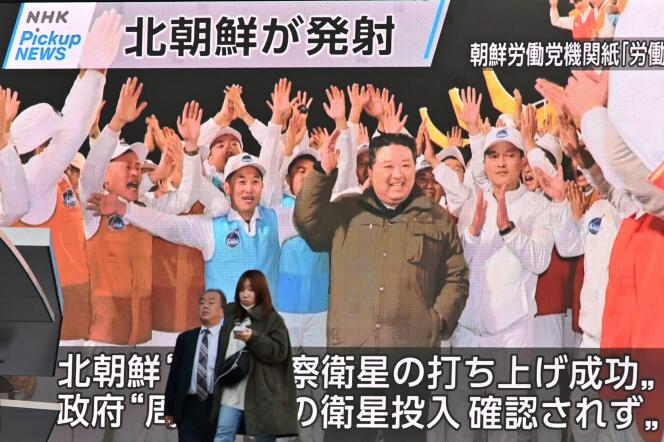 Pedestrians walk past a screen displaying North Korea's leader Kim Jong Un (center) celebrating after the reconnaissance satellite 'Malligyong-1' was launched, in the Akihabara district of Tokyo on November 22, 2023. 