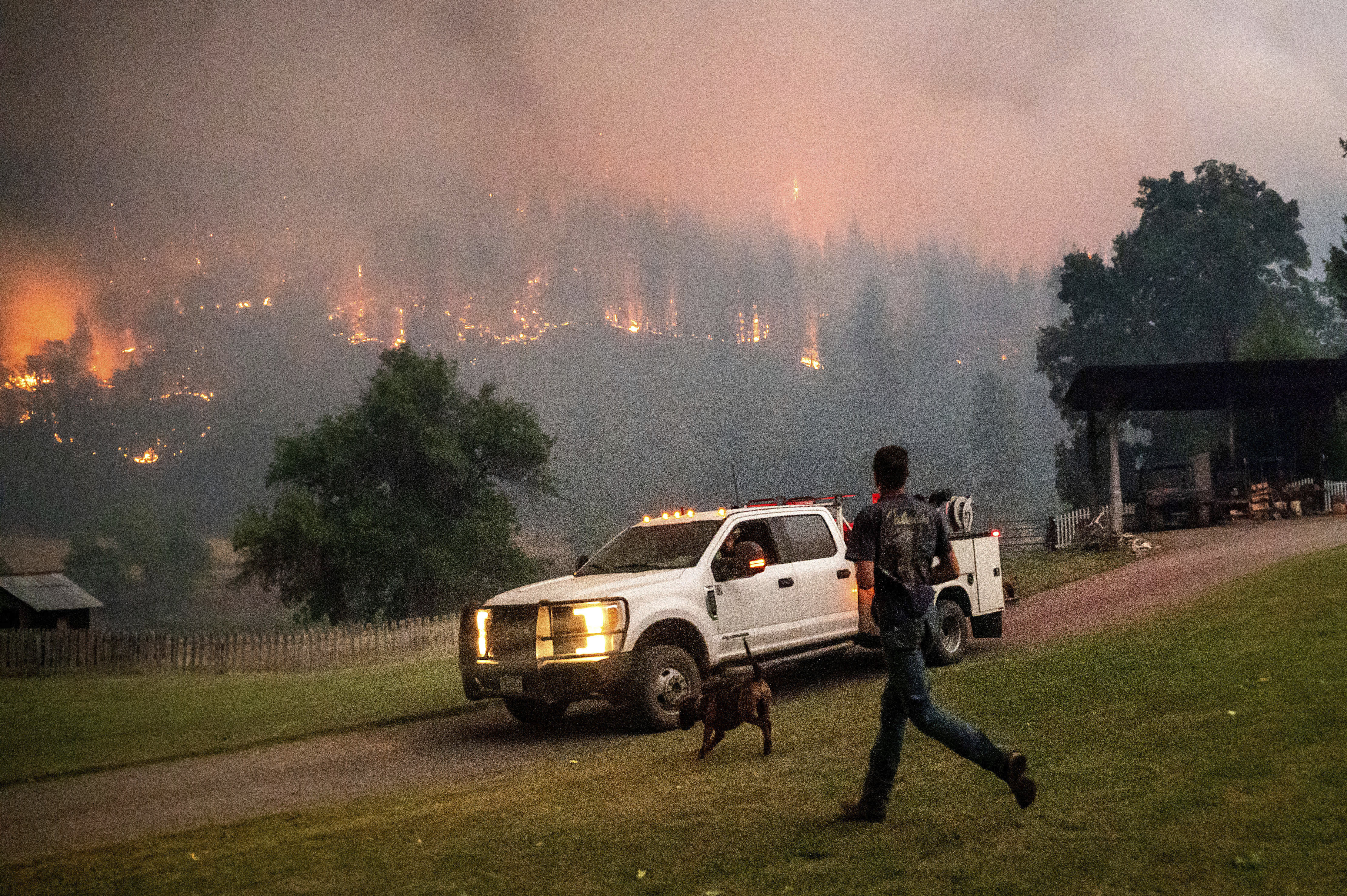 A man runs to a truck as a wildfire called the McKinney fire burns in Klamath National Forest on July 30, 2022. (Noah Berger)