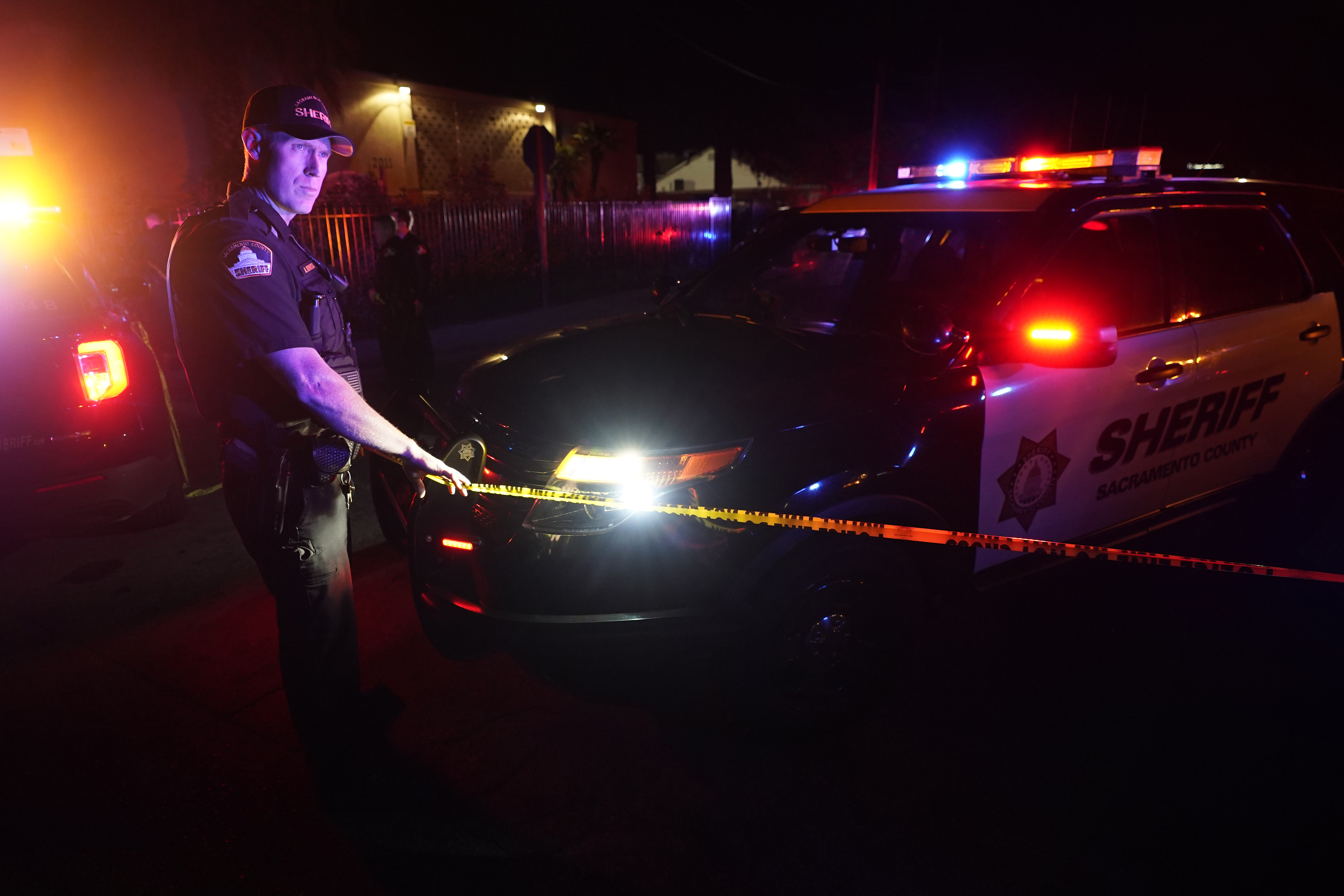 A Sacramento County Sheriff's deputy puts up police tape that blocks the street leading to a church where a fatal shooting occurred with multiple victims, in Sacramento, Calif., late Monday, Feb. 28, 2022. (AP Photo/Rich Pedroncelli)