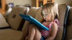 Little girl using tablet on couch 